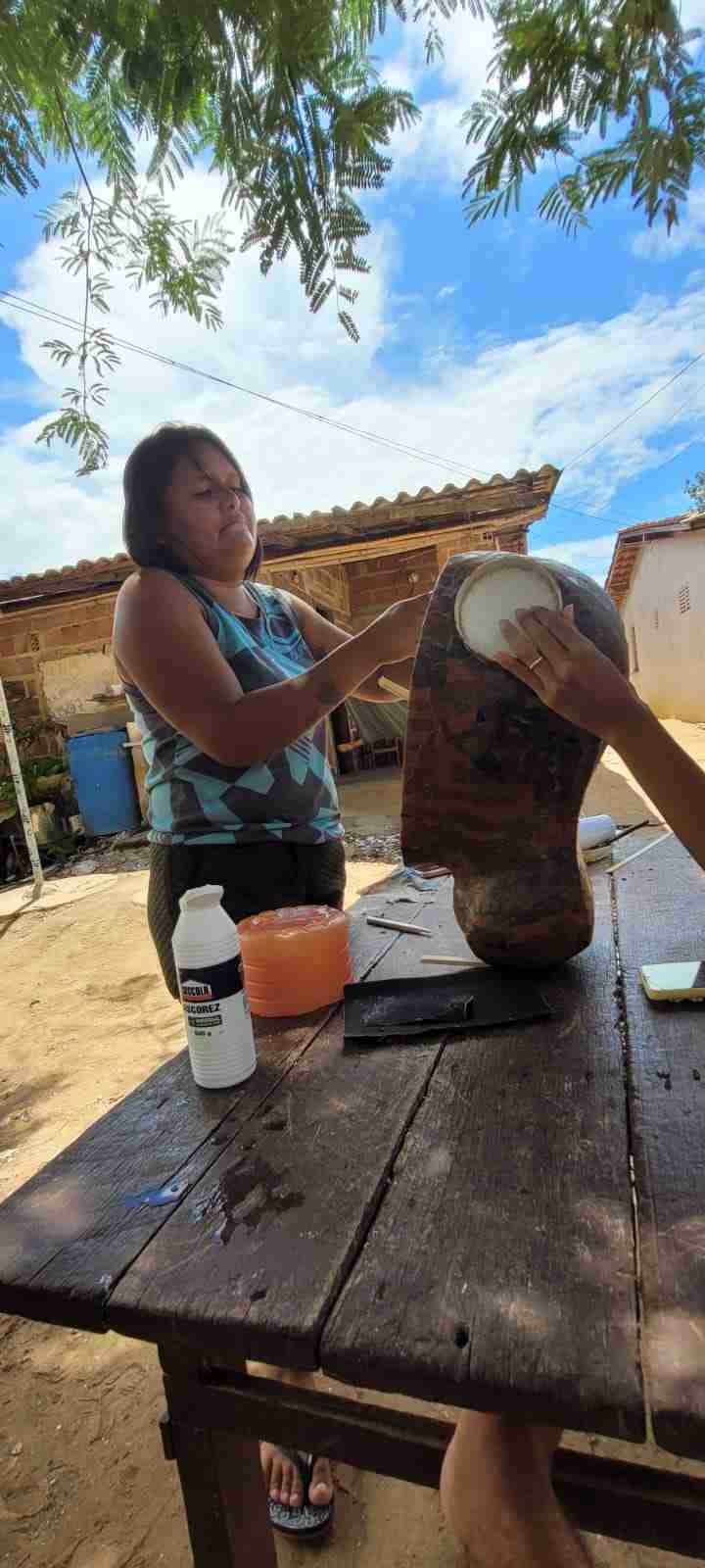 Woman painting a large traditional bull head decoration outdoors