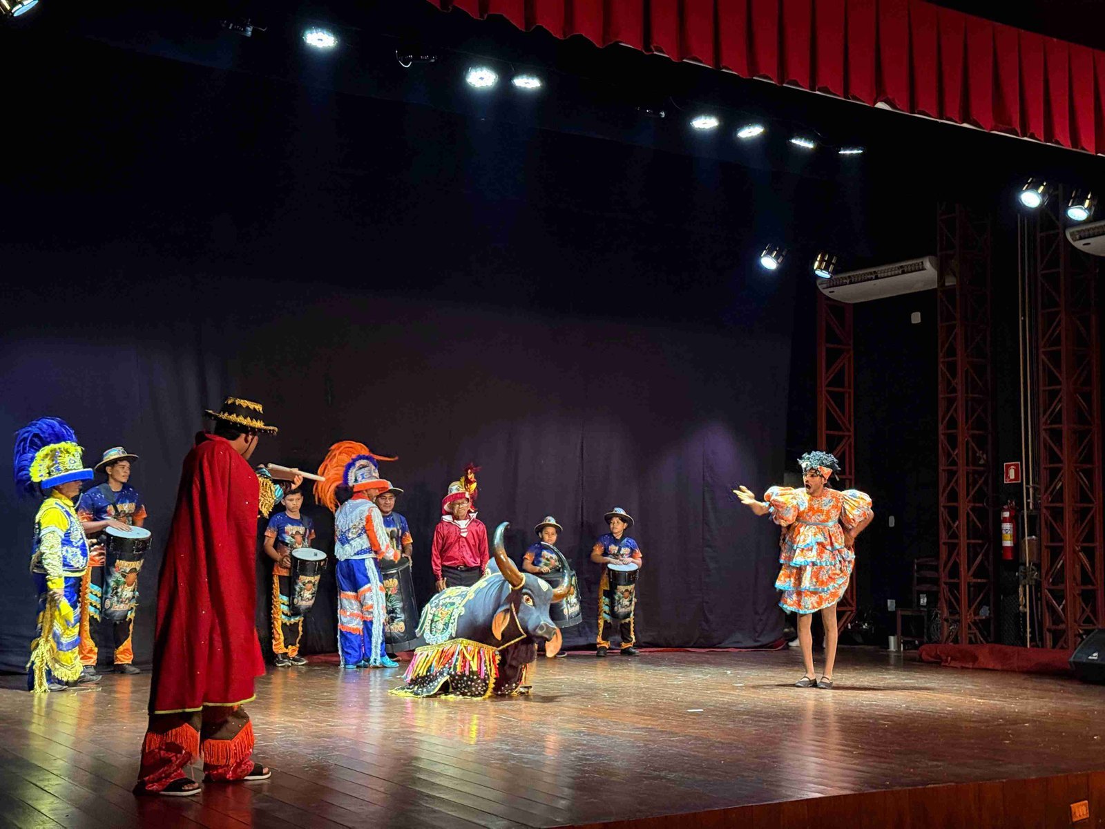 Cena teatral com o boi e danÃ§arina de branco no palco