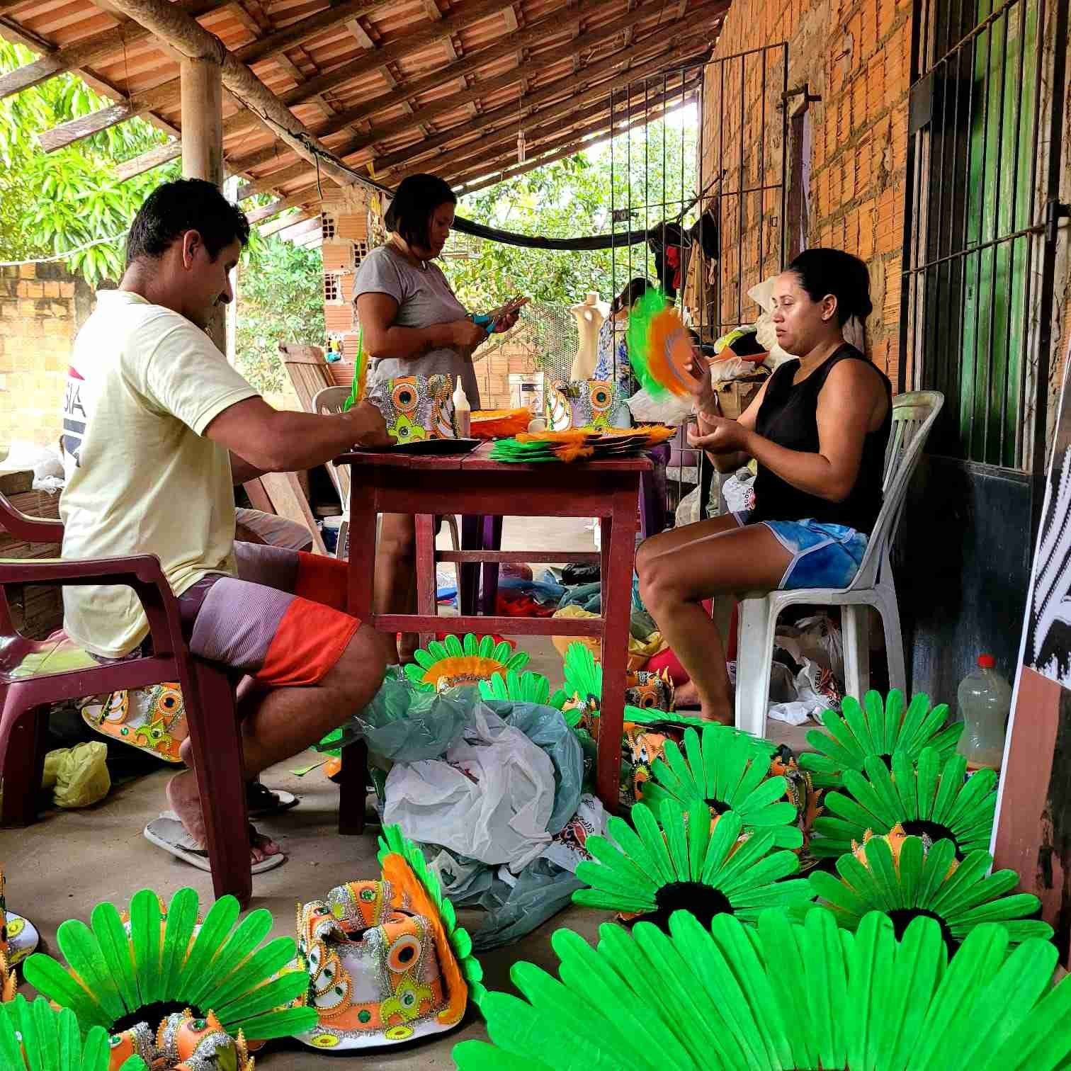 People crafting colorful green and orange feathered decorations indoors